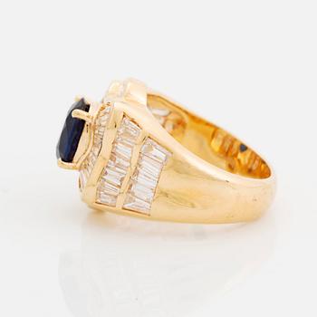 An 18K gold Junod ring set with a facted sapphire and tapered baguette-cut diamonds.