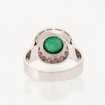 An 18K white gold ring set with a cabochon-cut emerald and round single-cut diamonds.