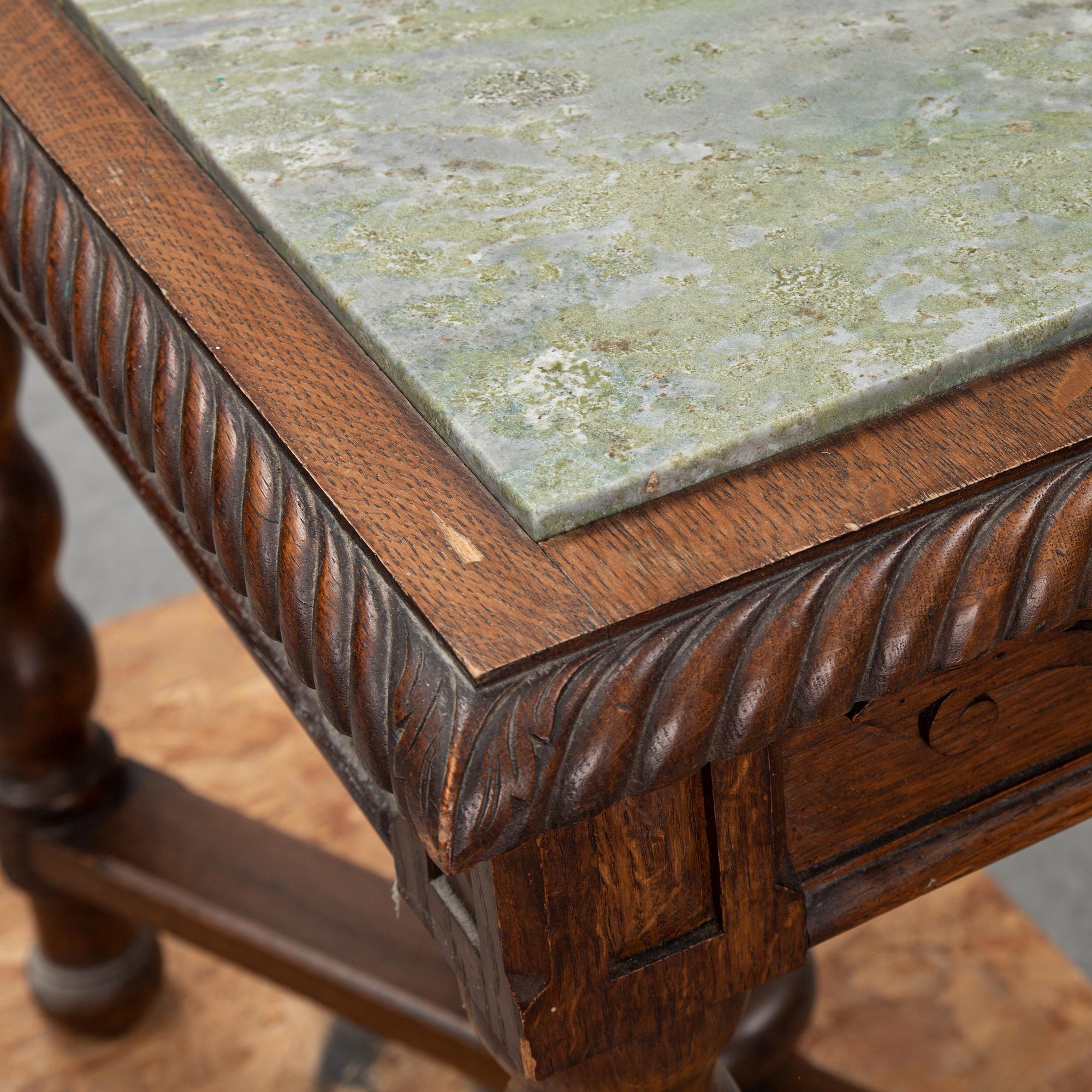 An early 20th Century oak side table with a stone top.