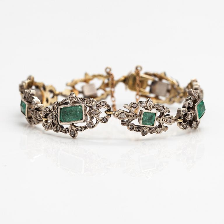 A 14K gold, silver bracelet with emeralds and diamonds.