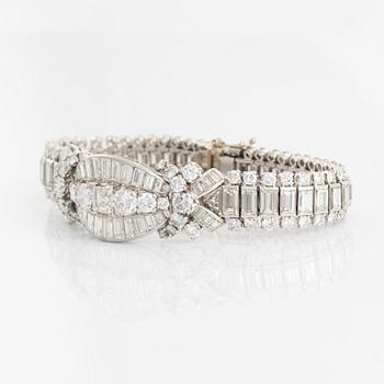 A platinum bracelet set with step-cut and brilliant-cut diamonds.