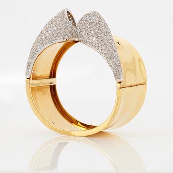 An 18K gold bangle set with round brilliant-cut diamonds.