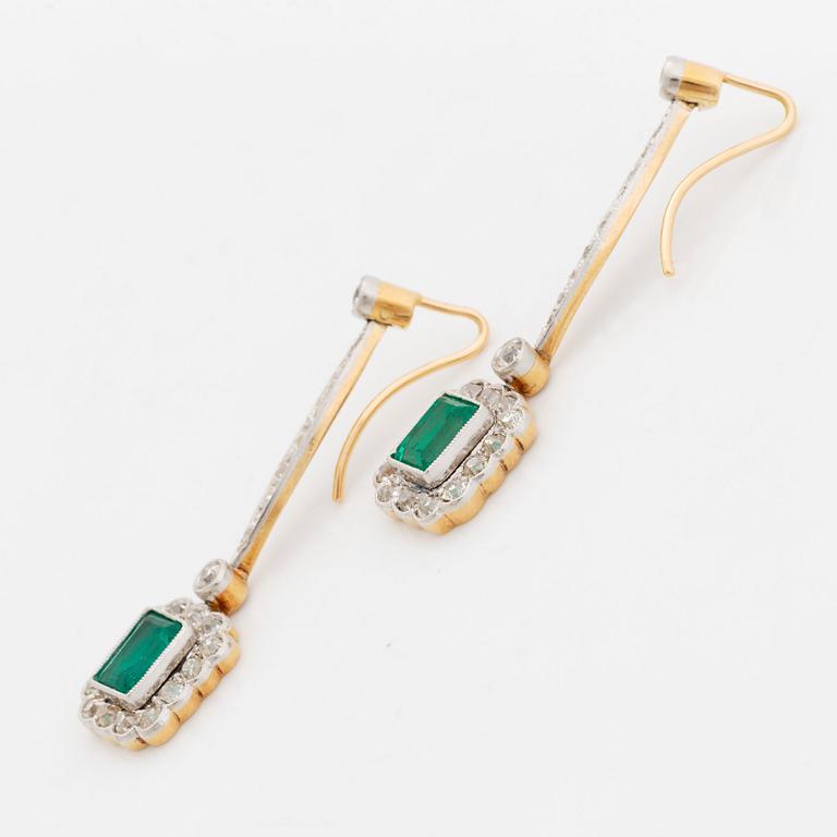 A pair of platinum and gold earrings set with step-cut emeralds and old-cut diamonds.