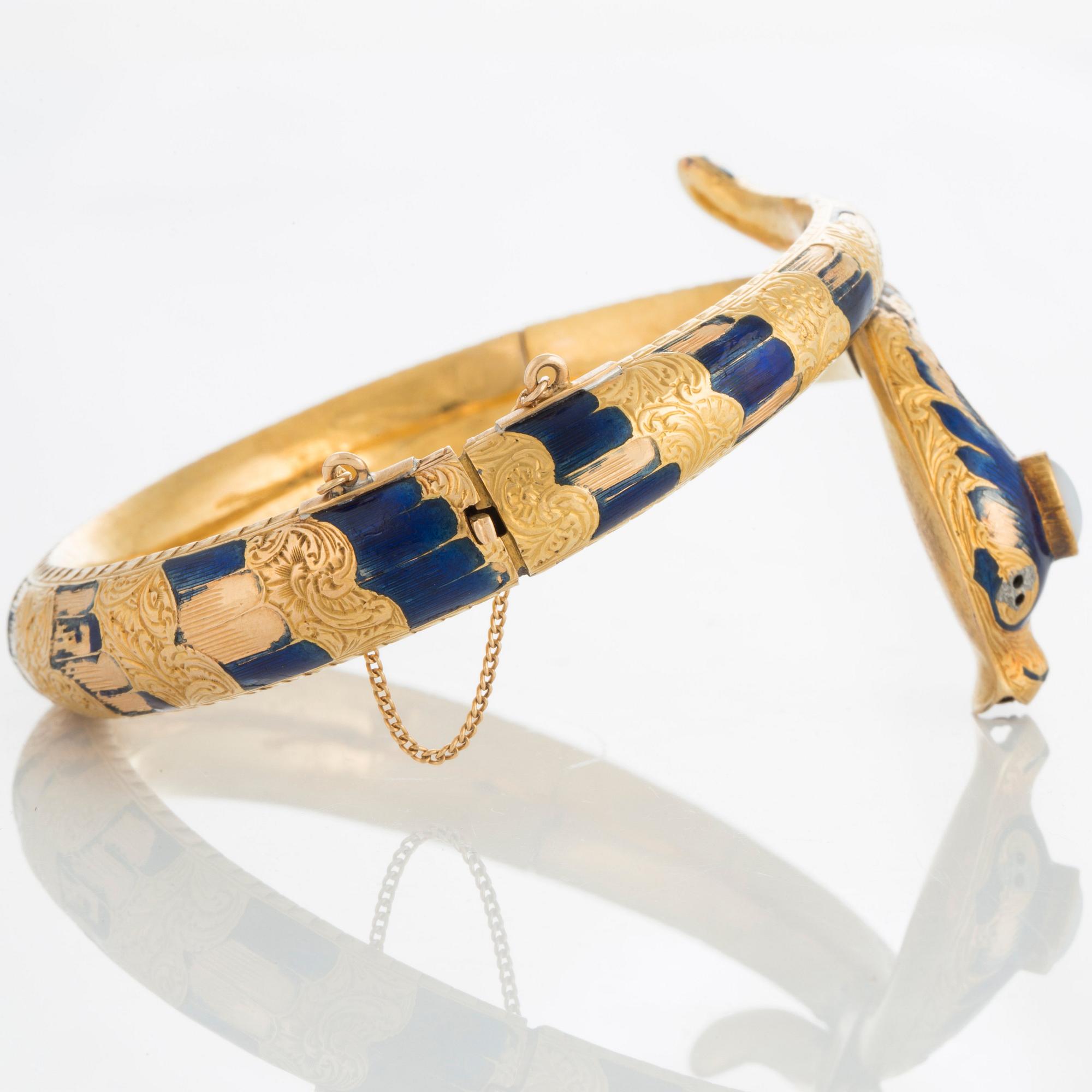 An 18K gold snake bangle decorated with blue enamel and set with an opal and a rose-cut diamond.