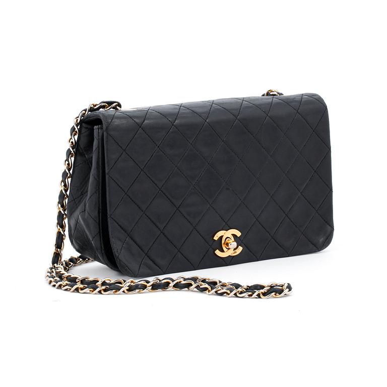 CHANEL, a black leather quilted purse with shoulder strap.