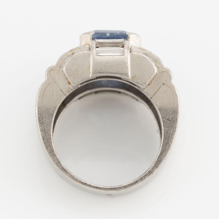 A platinum ring with a faceted sapphire and round brilliant-, eight-, and baguette-cut diamonds.