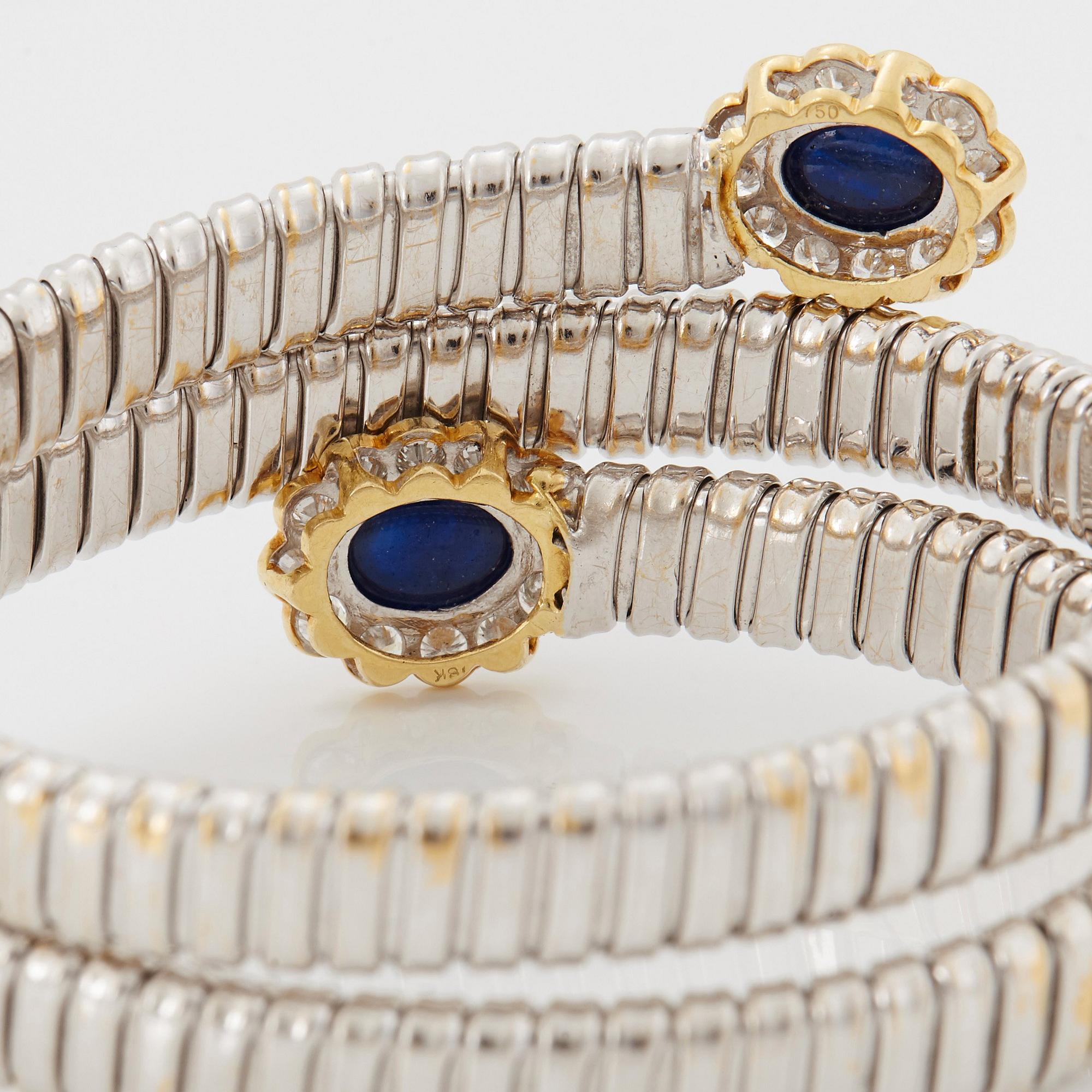 An 18K gold bangle set with cabochon-cut sapphires and round brilliant-cut diamonds.