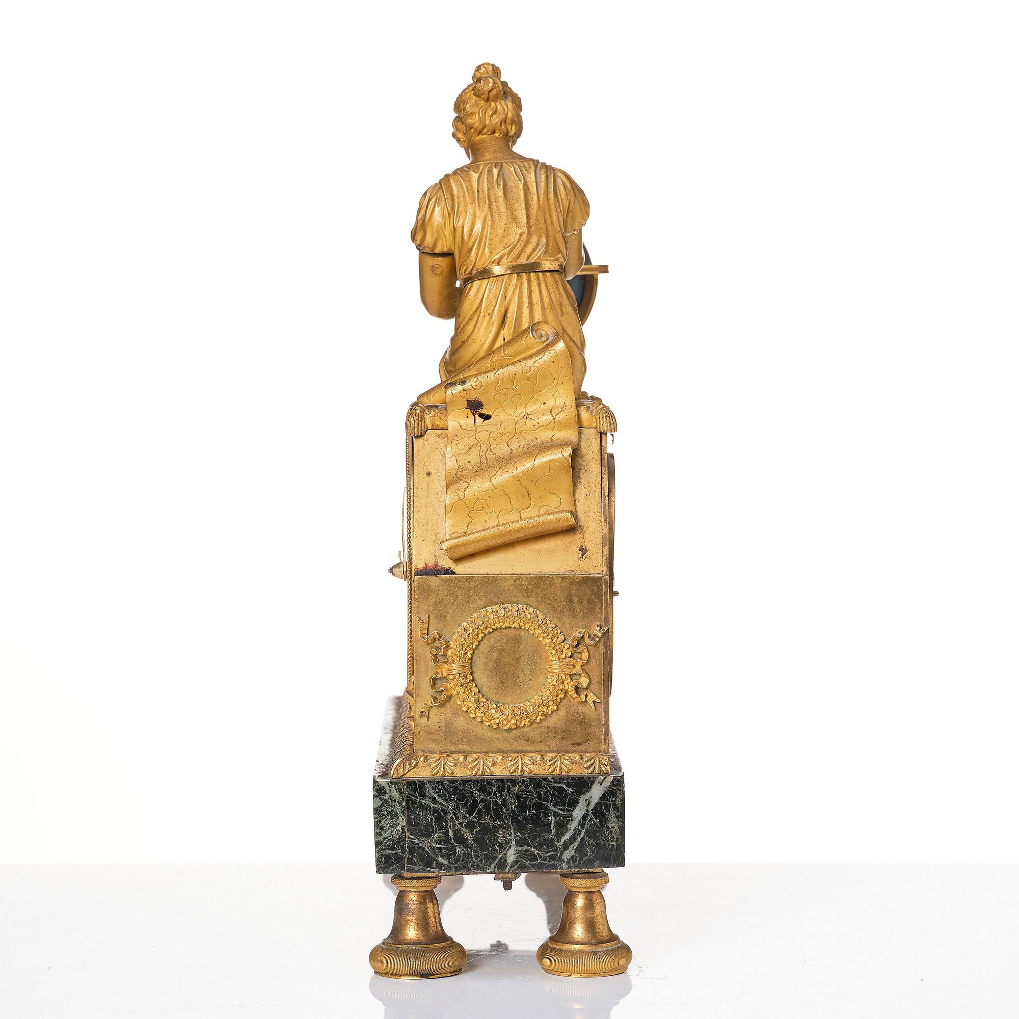 A patinated, ormolu, and marble French Empire figural mantel clock, early 19th century.