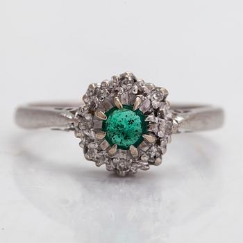 An 18K gold ring with an emerald and diamonds totalling approx. 0.04 ct.