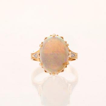 A 14K red and white gold ring with an oval-cut opal and round brilliant-cut diamonds.