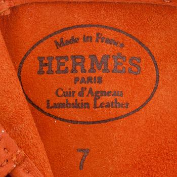 HERMÈS, a pair of orange lambskin leather gloves.