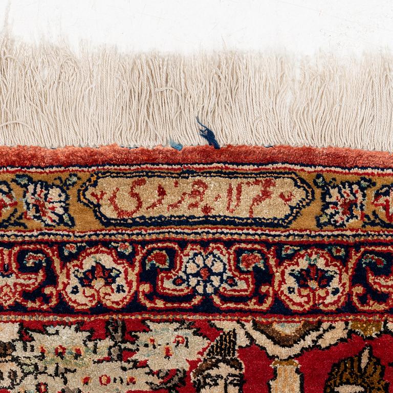 A signed semi-antique pictoral part silk Qum carpet, c. 341 x 224 cm.