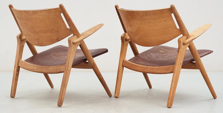 A pair of Hans J Wegner oak and brown leather easy chairs, Carl Hansen & Son, Denmark 1950's-60's.