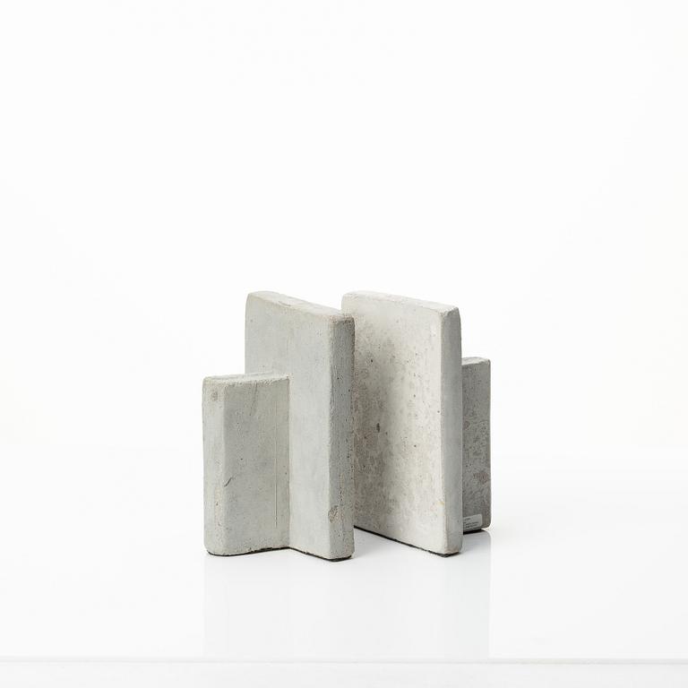 A mixed lot comprising a pair of limestone bookends, a bookshelf and two plates in concrete.