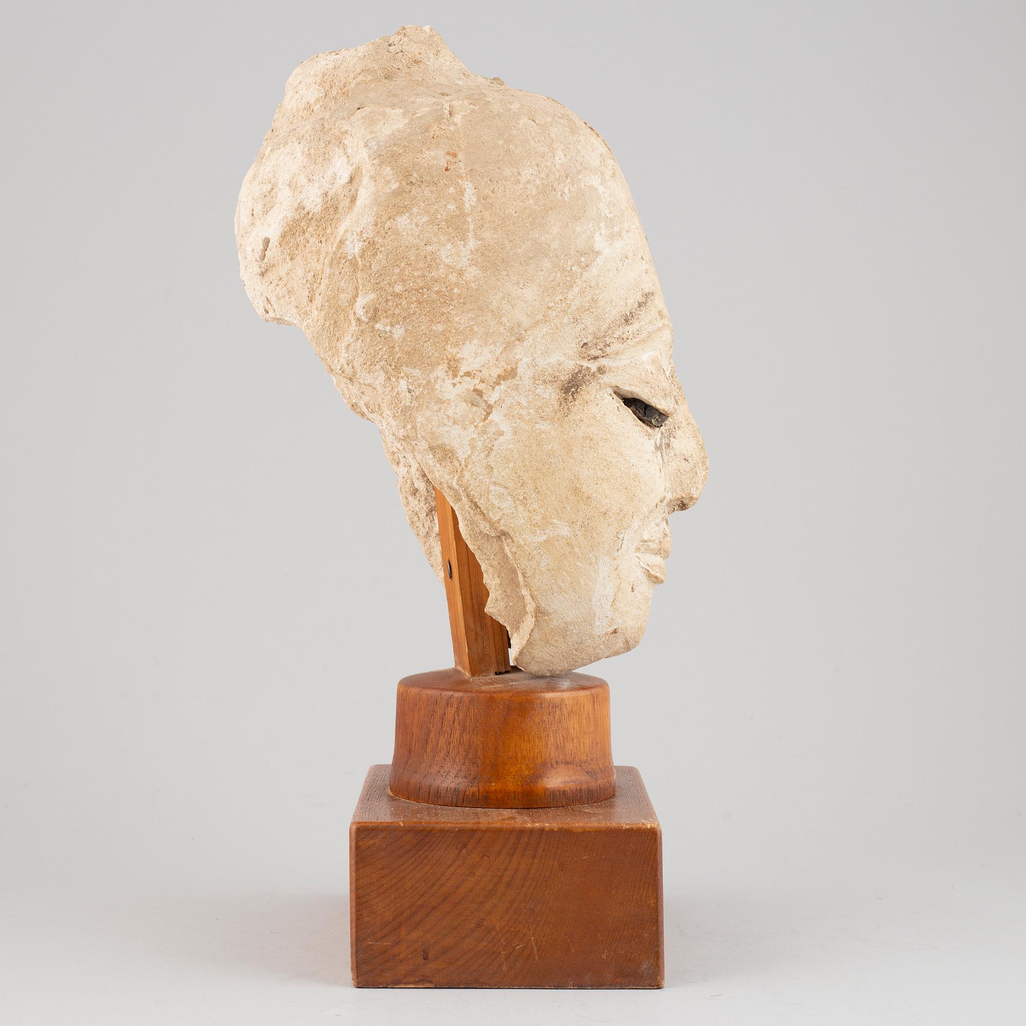 A South East Asian stone mass sculpture of a head, presumably modern manufacturing.