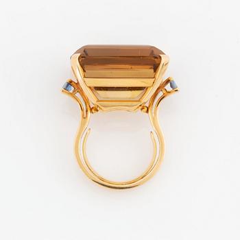An 18K gold ring set with a faceted citrine and two sapphires.