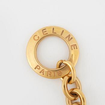 CÈLINE, a gold colored bracelet with pendants.