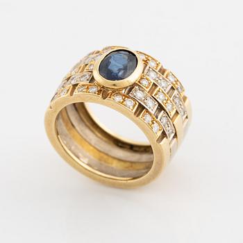 An 18K gold ring set with a faceted sapphire and round brilliant-cut diamonds.