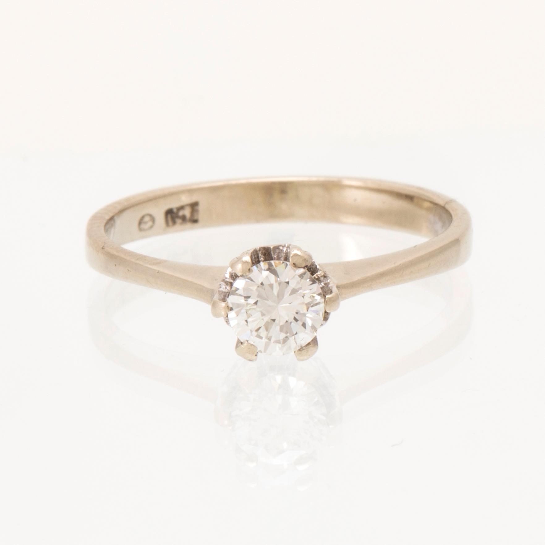 An 18K white gold solitaire ring set with a round brilliant-cut diamond.