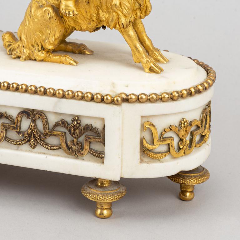A marble and gilt bronze mantle clock in Louis XVI style, decorated with grapes, putti and a bacchant, 19th century.