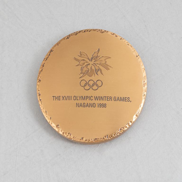 Deltagarmedalj OS Nagano 1998 samt ett tygmärke för den Svenska OS-truppen.