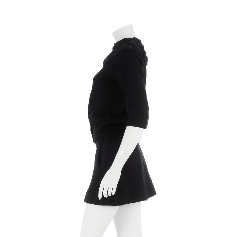 CHANEL, a black cashmere carding and a bouclé skirt.