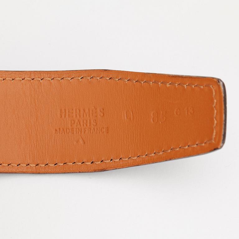 HERMÈS, a lilac crocodile belt with silver colored H-buckle.