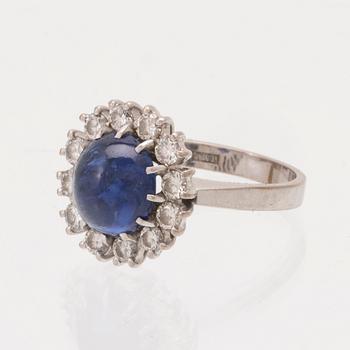 An 18K white gold ring set with a cabochon cut sapphire and round brilliant cut diamonds.