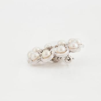 A brooch set with cultured pearls and round, brilliant-cut diamonds.