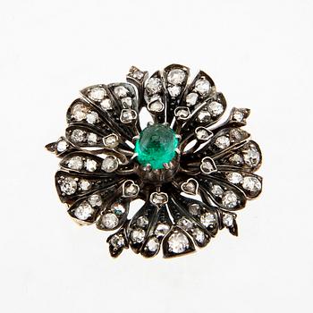 A 14K gold brooch set with a cabochon-cut emerald and old-cut as well as rose-cut diamonds.
