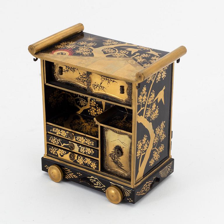 A group of Japanese lacquered miniature furniture and boxes in wooden crates, early 20th Century.