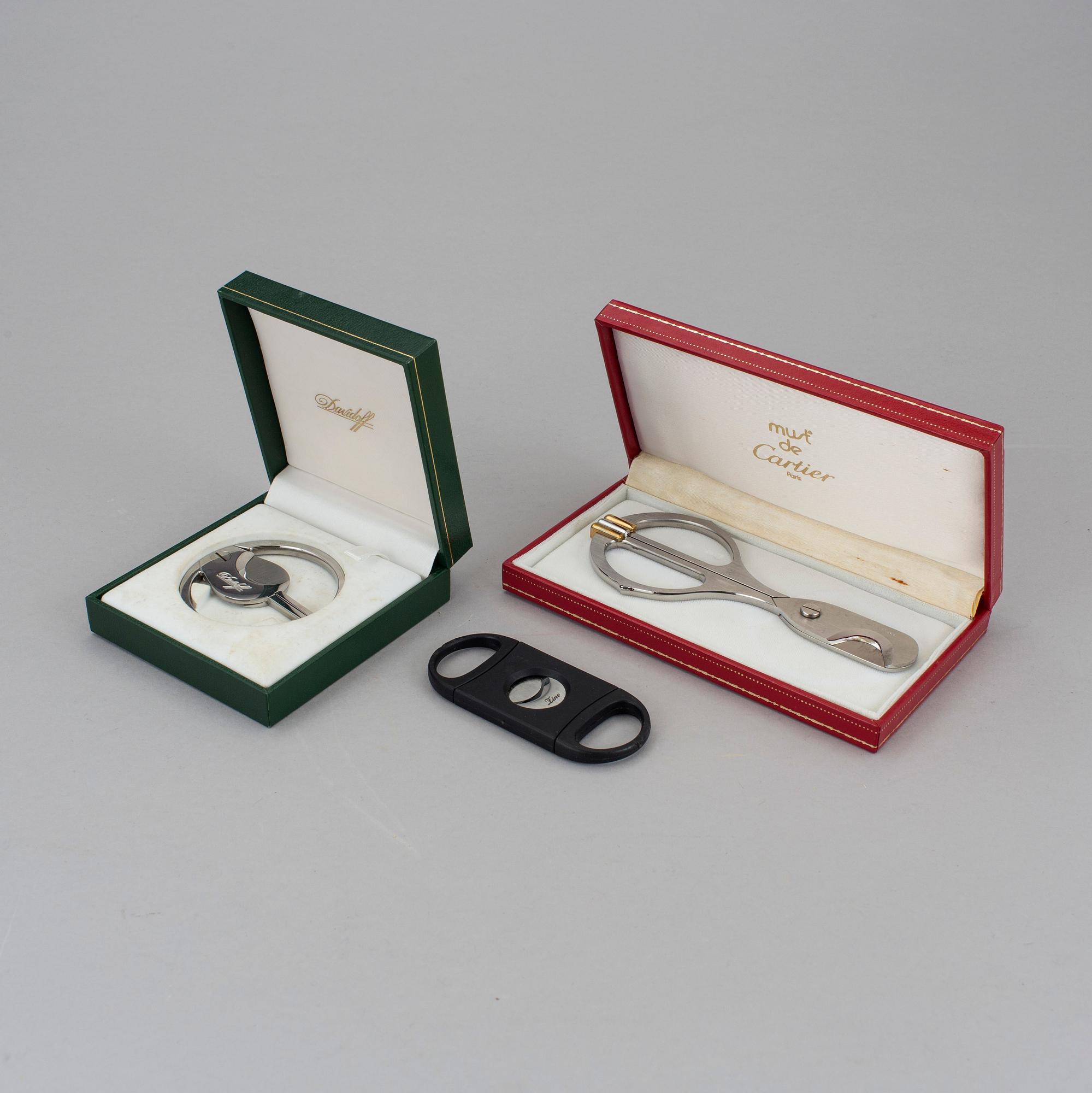Two cigar cutters from Davidoff and must de Cartier in original cases.