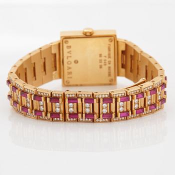 A Bulgari wristwatch in 18K gold set with step-cut rubies and round brilliant-cut diamonds.