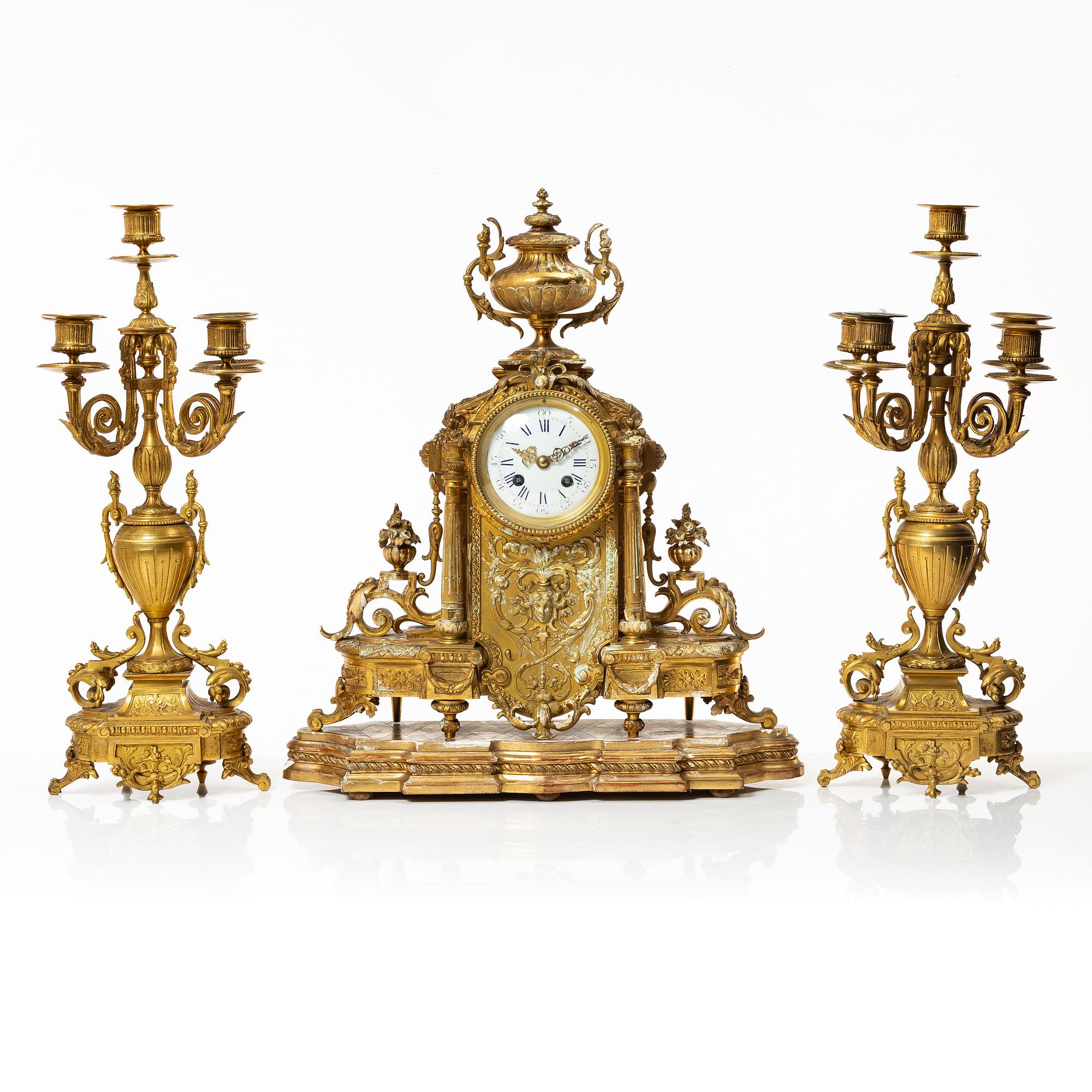 A mantle clock and a pair of candelabra, Louis XVI style, ca 1900.