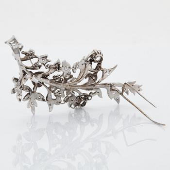 An 18K white gold brooch set with round brilliant-cut diamonds.