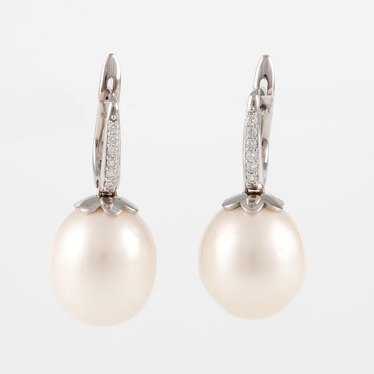 A pair of 18K gold earrings with cultured freshwater pearls and round brilliant-cut diamonds.