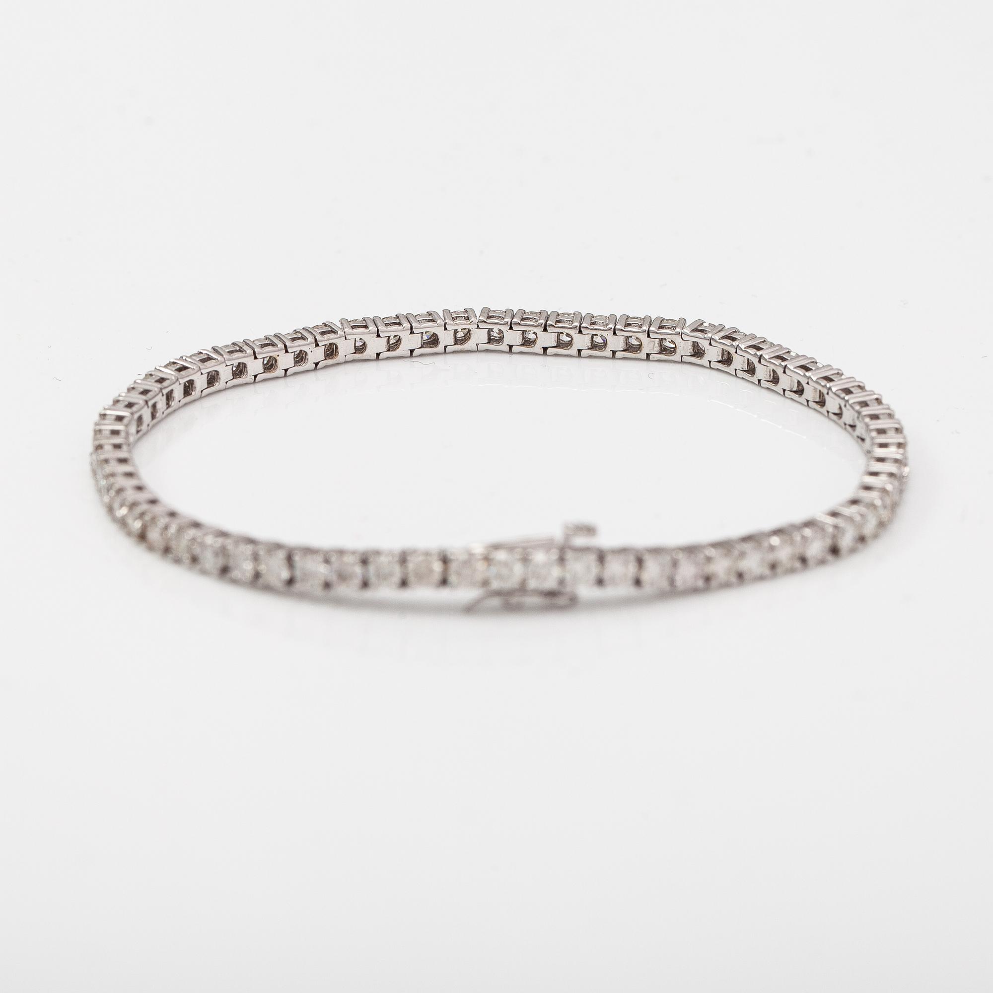 Tennisrannekoru, 14K valkokultaa, timantteja n. 6.10 ct yht. AIG -todistuksella.