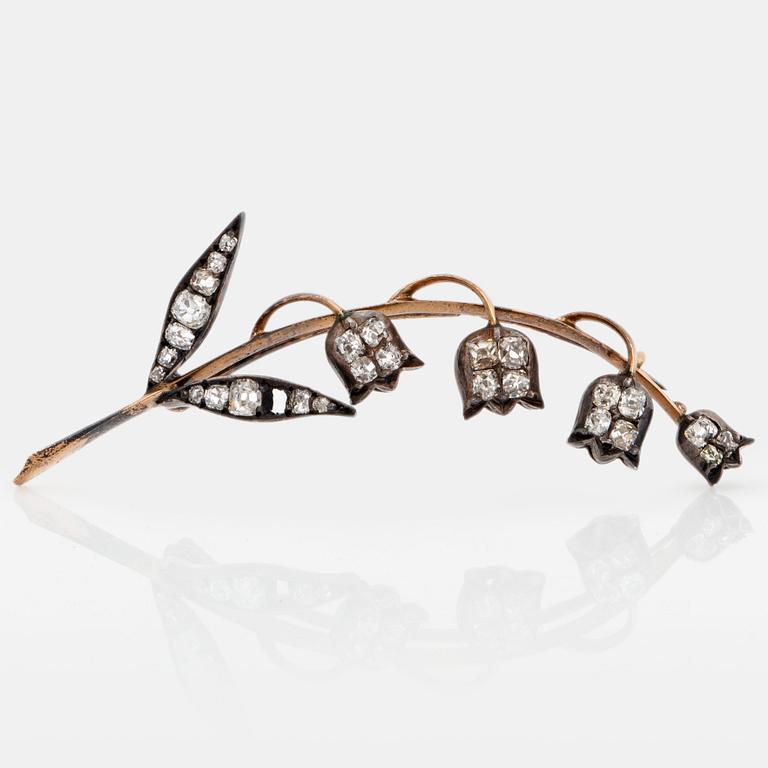 A brooch in 14K gold and silver set with old-cut diamonds, in the shape of a lily-of-the valley twig.