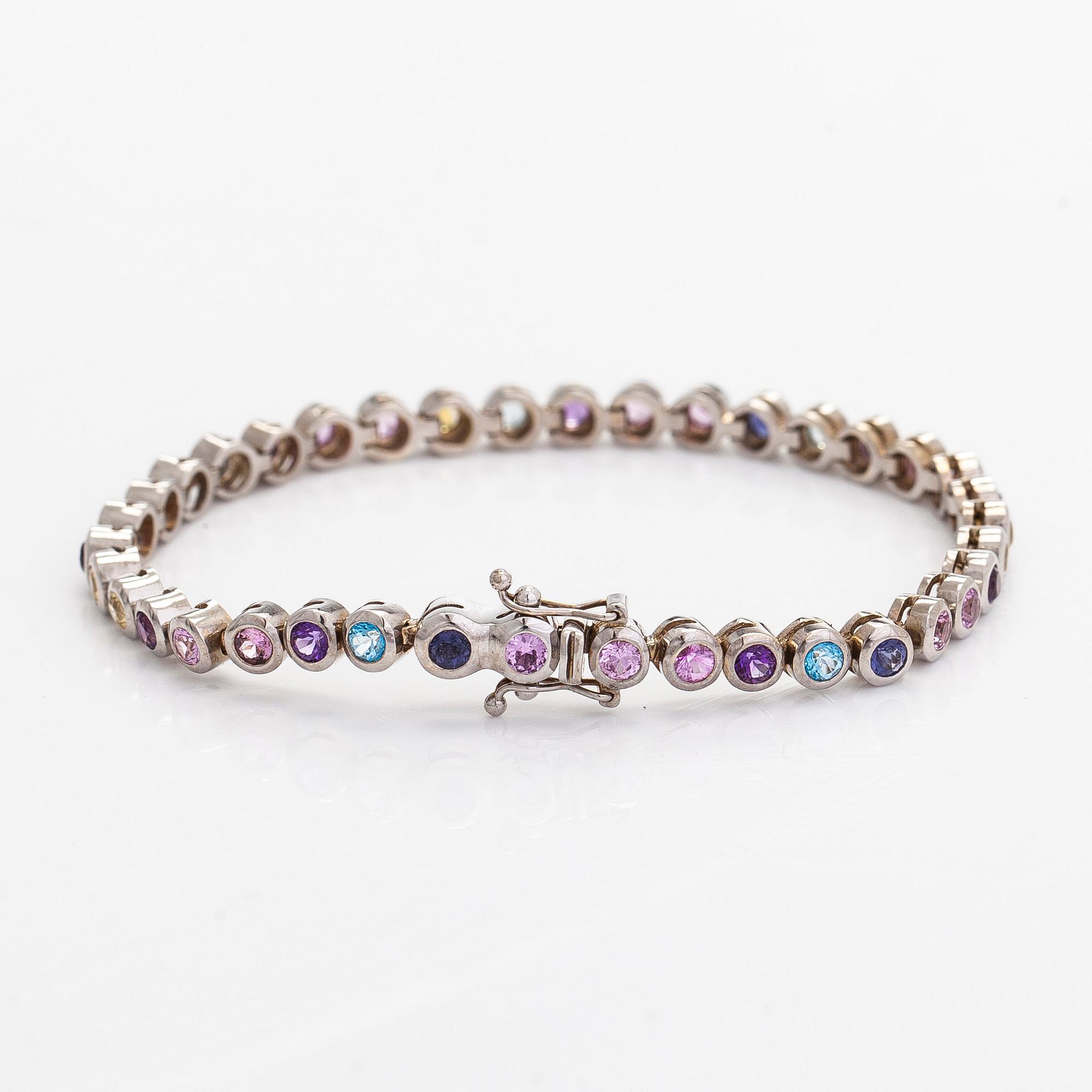 Rannekoru, 18K valkokultaa ja monivärisiä kiviä.