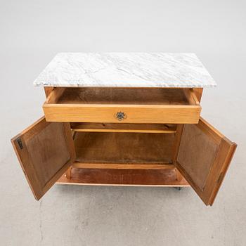 An early 1900s oak and marble cabinet.