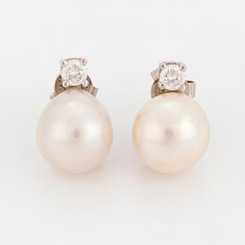 A pair of earrings set with cultured pearls and round, brilliant-cut diamonds.