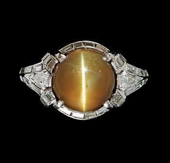 A 6.75 cts cabochon-cut chrysoberyl cat's-eye and diamond ring. Diamonds total carat weight circa 1.00 ct.