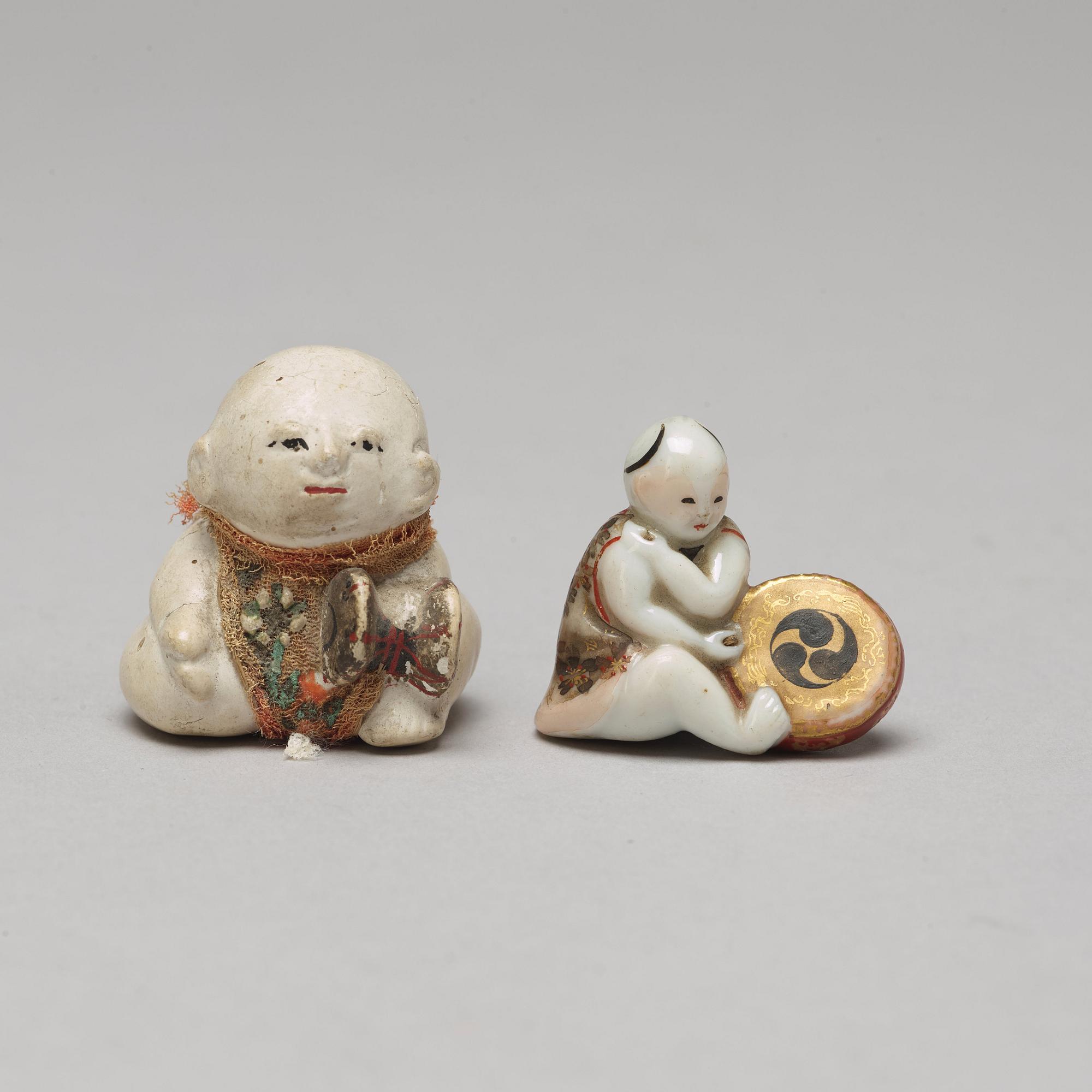 A set of two Japanese figures and a set of six cups in a wooden box, early 20th Century.