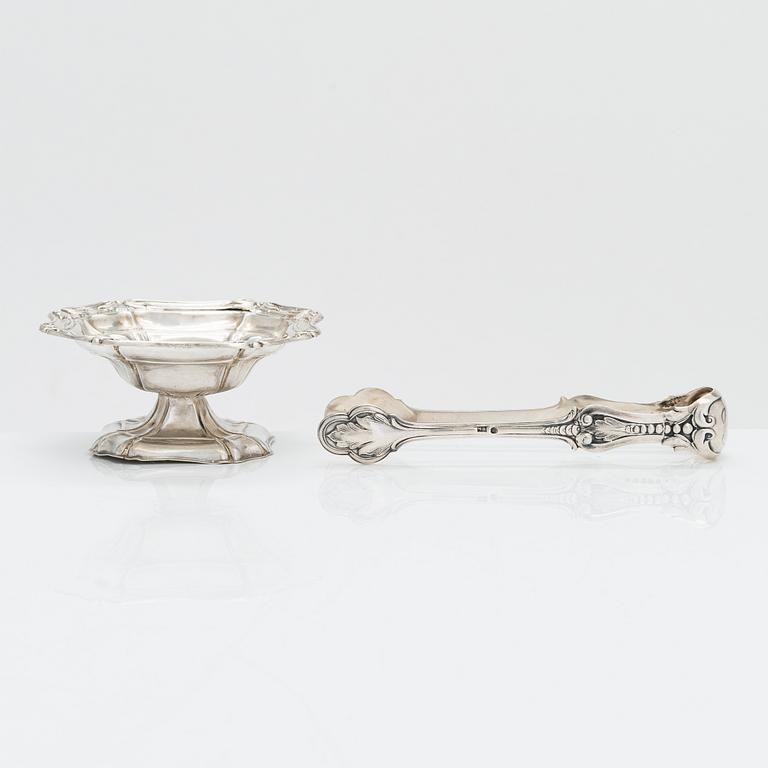 A silver sugar tong by Johan Warjus, and a silver salt cellar by Adolf Sper, St Petersburg 1856 and 1849.
