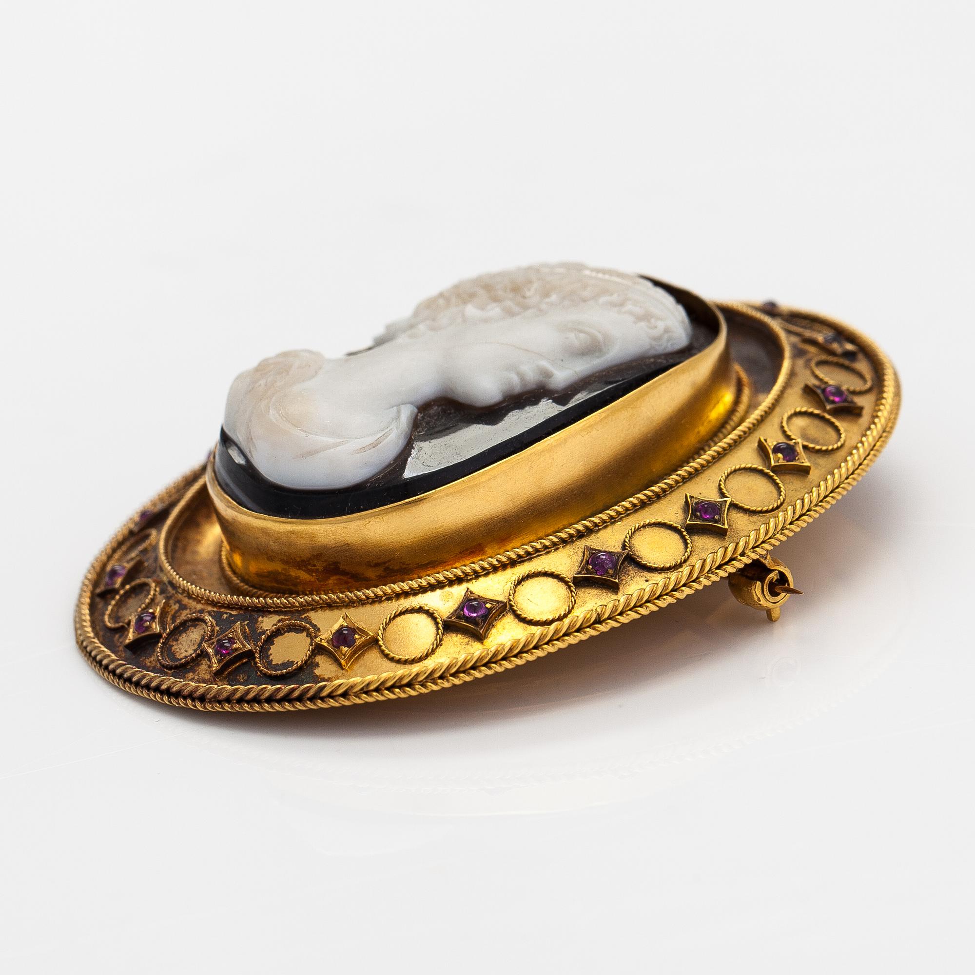 An 18K gold brooch with an onyx cameo and rubies.