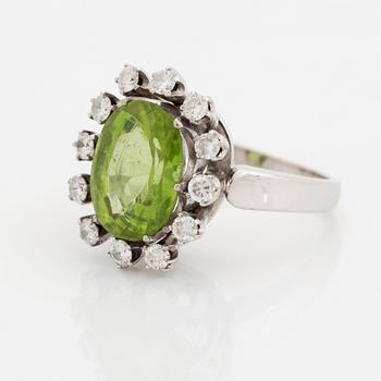 An 18K white gold ring set with a faceted peridot and round brilliant-cut diamonds.