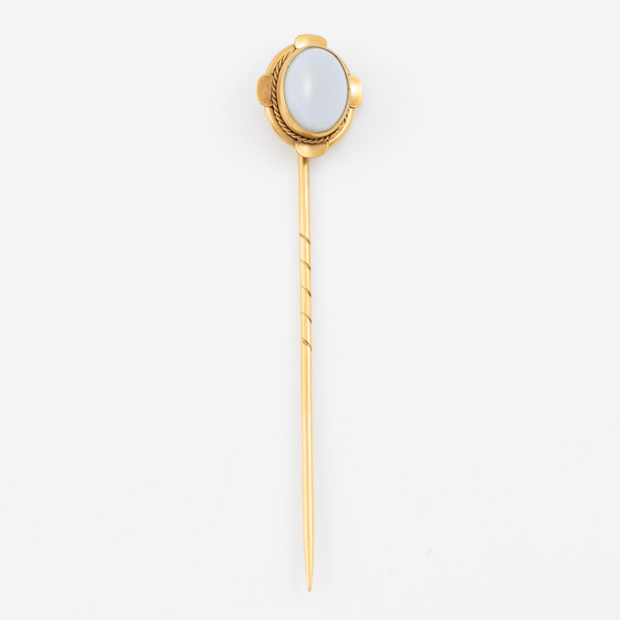 Brooch pin of low-grade gold with a white-blue stone.