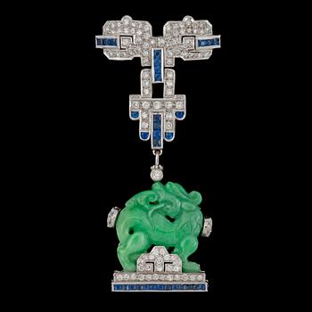 861. BROSCH med snidad obehandlad jade i form av en drakhund omgärdad av carréslipade safirer och briljantslipade diamanter.