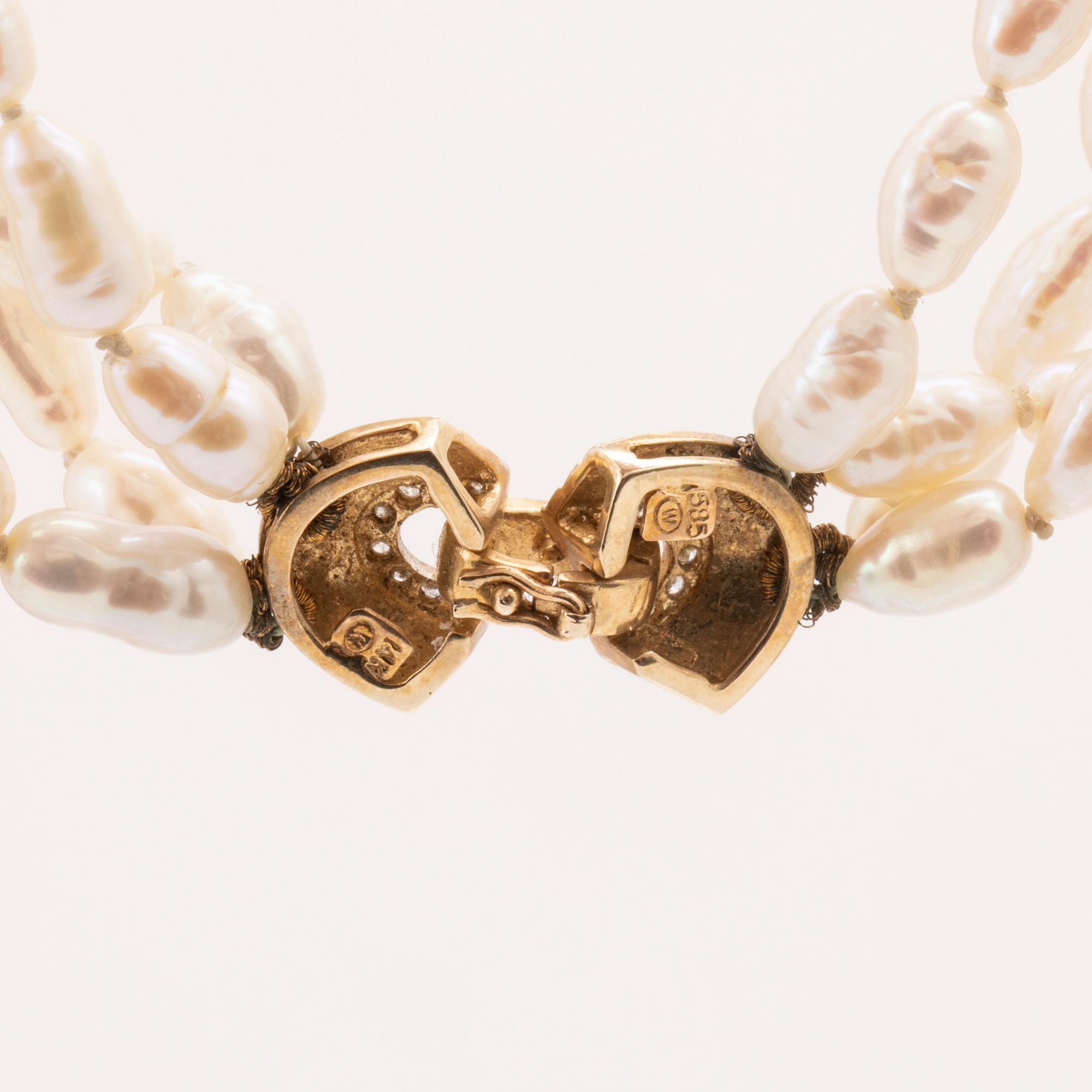 A necklace of cultured pearls set with a 14K gold lock and round brilliant cut diamonds.