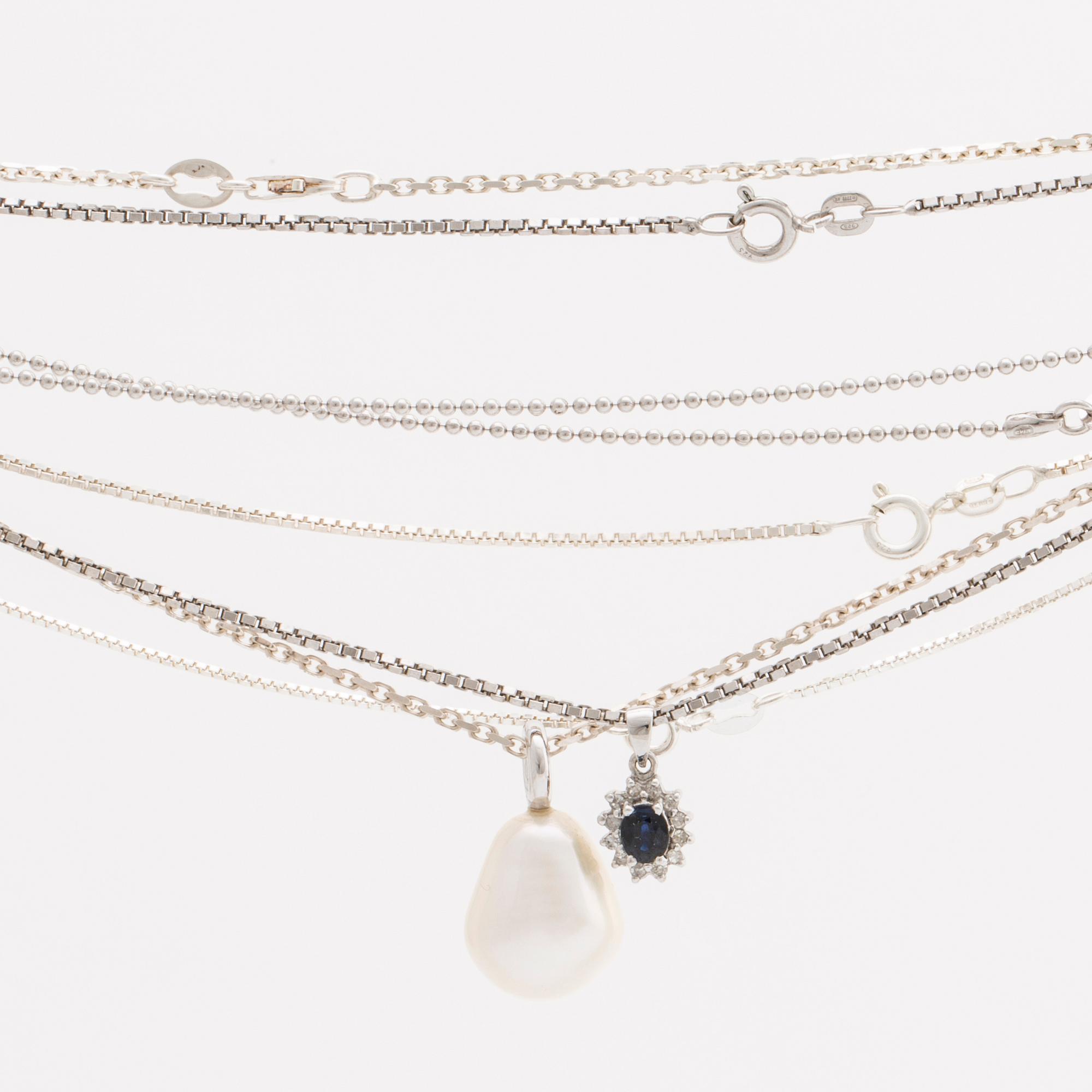 2 pendants 18K whitegold with 1 cultured pearl approx 13,5 mm and 1 sapphire approx 4x3 mm and diamonds, 5 silver chains.
